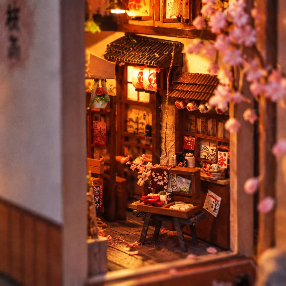 Inside Sakura Rain: a little shop counter under lanterns and pink blossoms