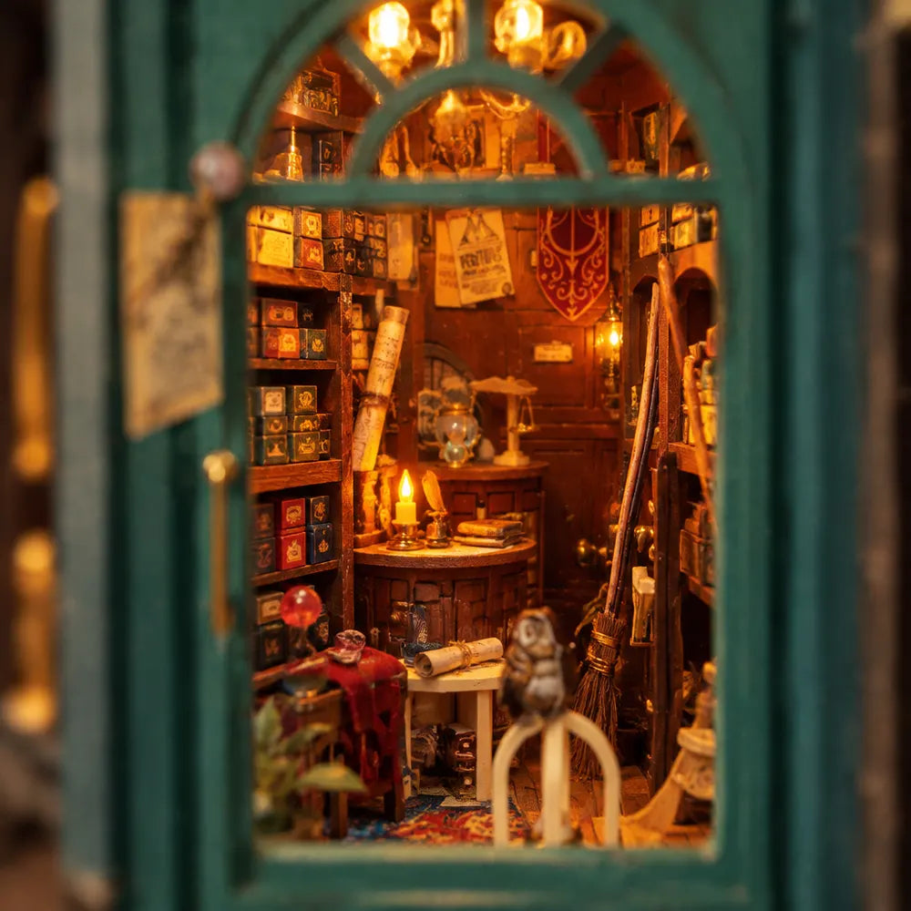 Inside The Sorcerer's Shop: shelves of little boxes, brooms and a lit candle behind a green door